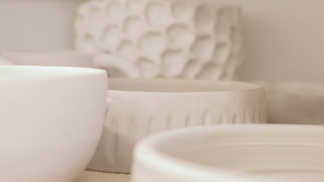 Cream ceramic bowls and a textured vessel in soft light