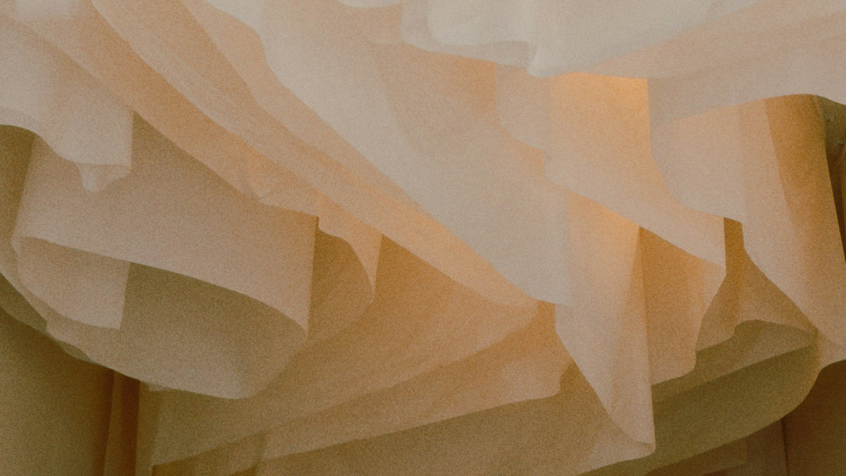 Layers of sheer ivory fabric cascading in soft warm light
